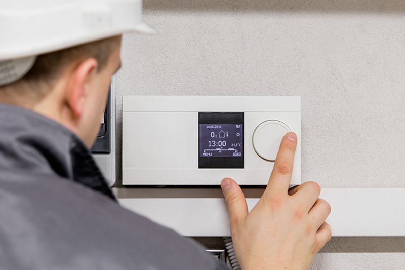 Image of technician working with thermostat. Why Schedule Air Conditioning Maintenance?.