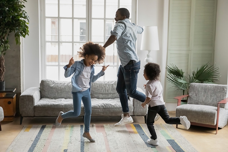 What Are Air Scrubbers? Dad and two kids dancing and jumping in living room.