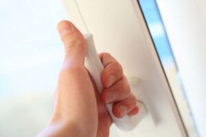 hand opening a window in a home.