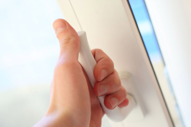 hand opening a window in a home.
